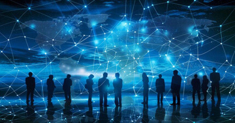 Silhouettes of people standing before a glowing global network