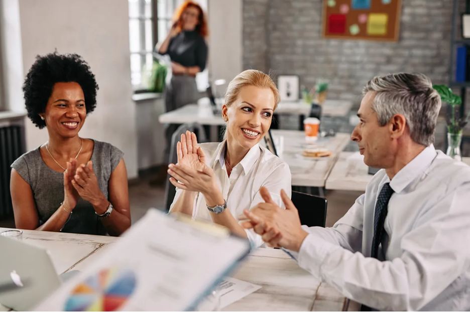 Colleagues collaborating and celebrating around a table in an office setting