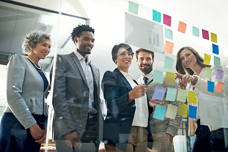 A team of professionals collaborating around notes on a glass wall