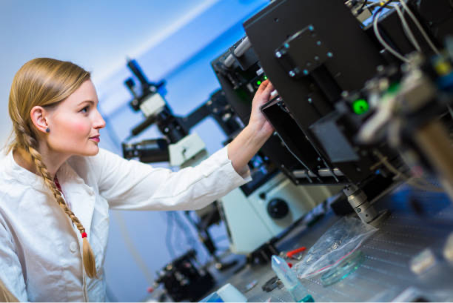 A researcher in a lab coat working with quantum optics laser equipment on a lab bench