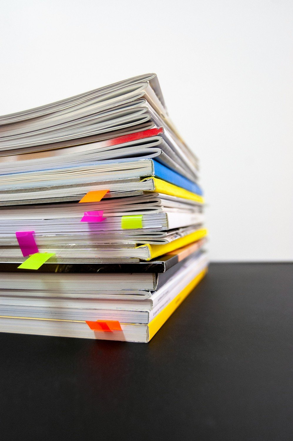 A stack of documents and reports with colorful sticky tabs